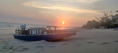a boat on the beach with the sunset in the background at Pousada Kasabela Residence in Prea