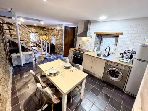 a kitchen with a table and a sink and a dishwasher at Casita con encanto, les gaites in Collanzo