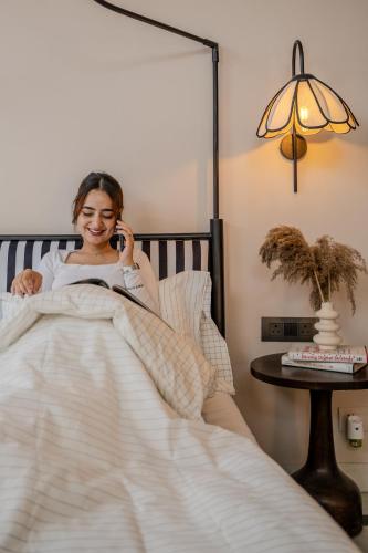 a woman laying in bed talking on a cell phone at 3000Sqft Ultra Luxury Apartment with Private Cinema In Delhi Poshest Locality Greater Kailash 2 in Jāmb