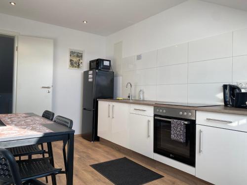 a kitchen with a black refrigerator and a table at Zimmervermietung Lösken in Duisburg
