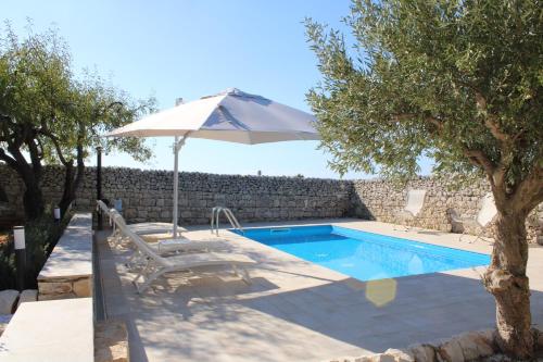 a swimming pool with an umbrella and a chair at Villa Quartarella - La bellezza nel silenzio - piscina in Michelica
