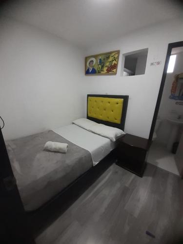 a small bedroom with a bed with a yellow headboard at HOTEl LAS FLORES in Santa Rosa de Cabal