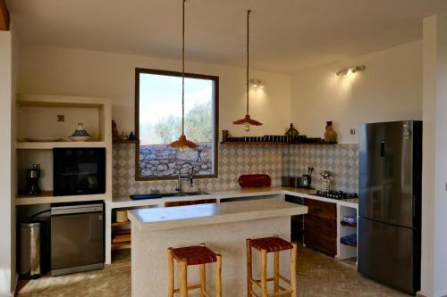 a kitchen with a refrigerator and two bar stools at Charming Beldi villa with pool in Sidi Kaouki
