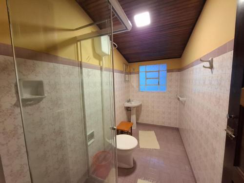 a bathroom with a toilet and a glass shower at Pousada Pedra da Gávea in Visconde De Maua