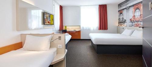 a hotel room with two beds and a window at B&B Hotel Łódź Centrum in Łódź