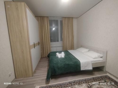 a bedroom with a bed with two towels on it at Мирный дом in Astana