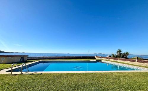 a swimming pool with the ocean in the background at Holibai Albatros, Dúplex al ladito del Mar, con terrazas y piscina, Baiona in Baredo