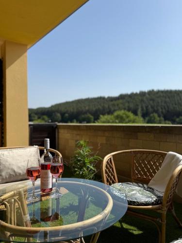 two glasses of wine on a glass table on a patio at Fonte Salis Apartman in Egerszalók