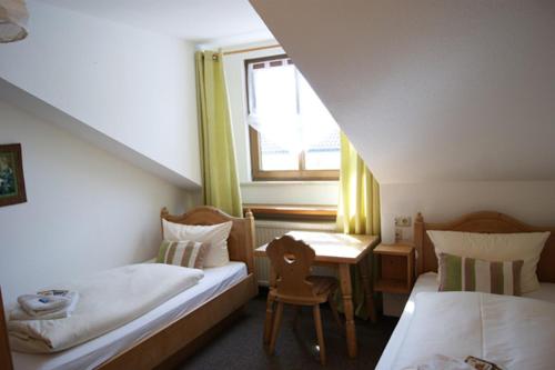 a bedroom with two beds and a table and a window at Gasthof zum Hirsch in Krugzell