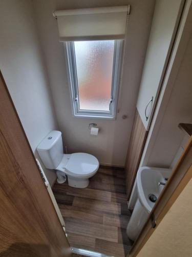 a bathroom with a toilet and a sink and a window at Coop129 Golden sands holiday park in Kinmel Bay