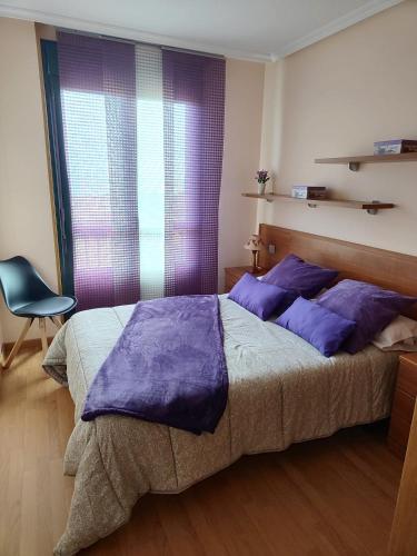 a bedroom with a large bed with purple pillows at Amanecer en Playa de LLás in Foz