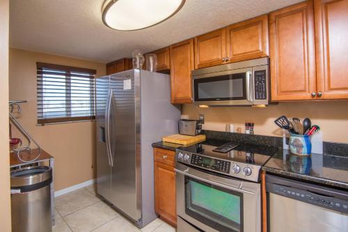 a kitchen with stainless steel appliances and wooden cabinets at Pier Point South Ocean View Townhouse Condo B-20 in Saint Augustine Beach