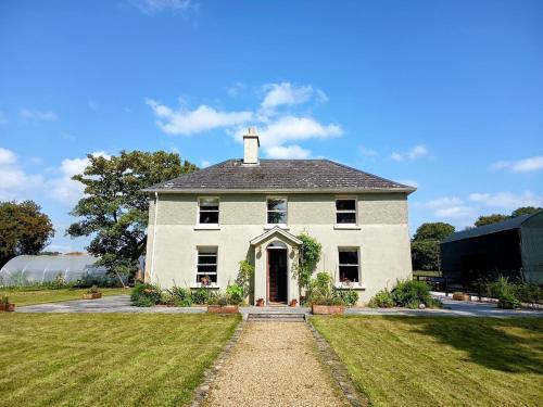 a large white house with a grass yard at 100 year old family farmhouse in Oldcastle