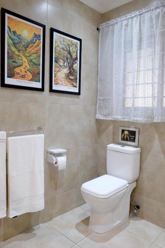 a bathroom with a toilet and two pictures on the wall at Simply The Choice Manor in Panorama