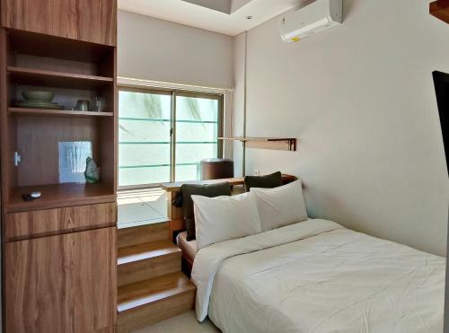 a small bedroom with a bed and a window at HŌM Coliving Bali in Kerobokan