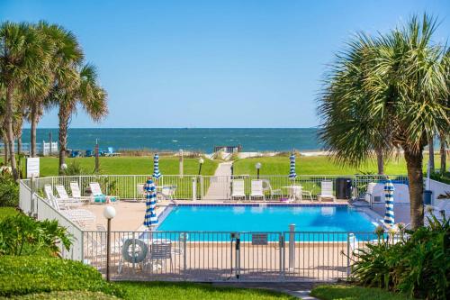 una piscina con sillas, palmeras y el océano en Pier Point South Ocean View Townhouse Condo C-33, en St. Augustine Beach