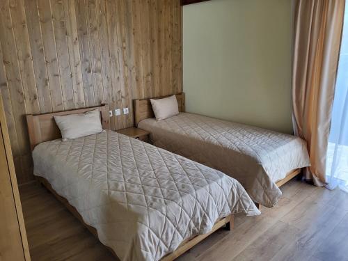two beds in a small room with wooden walls at Pirin Golf Villa Sokol in Bansko