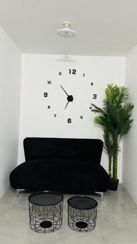 a black couch with a clock on a wall at Comfortable house in Zaragoza