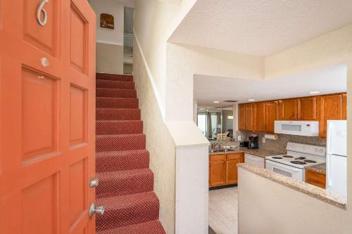 un escalier dans une cuisine avec une porte rouge dans l'établissement Pier Point South Oceanfront Townhouse Condo A-6, à Saint Augustine Beach