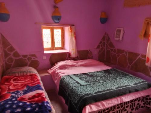 a bedroom with purple walls and two beds in it at Auberge Tafouyt in Tamtetoucht
