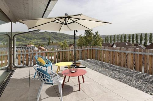 eine Terrasse mit Tisch und Stühlen und einem Sonnenschirm in der Unterkunft Penthouse Panorama Deluxe - Seesicht - BBQ - Beach Paradise - Loft Premium in Öhningen