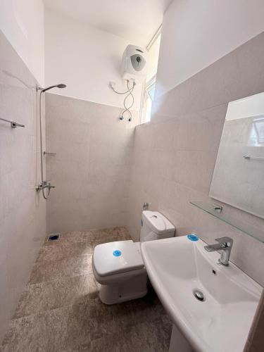 a white bathroom with a toilet and a sink at Wellness Residencies in Colombo