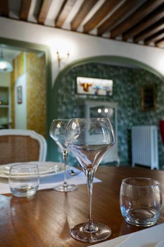 two wine glasses sitting on a wooden table at Gîte de charme Autun'Home in Autun