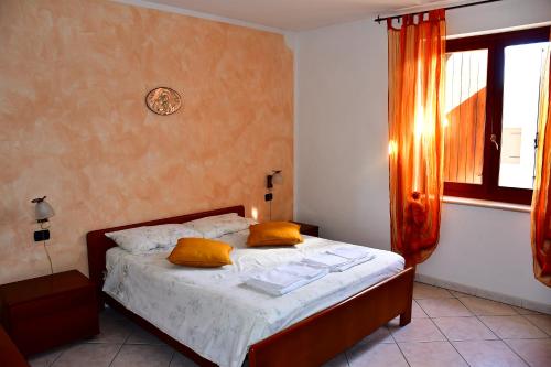 a bedroom with a bed with yellow pillows and a window at La casa dei nonni in Soave