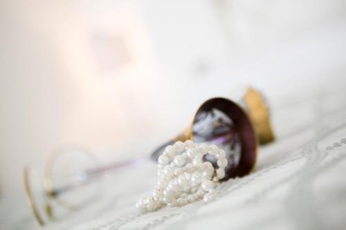 a pearl necklace and glasses sitting on a bed at B&B Casa Dei Grilli in Longiano
