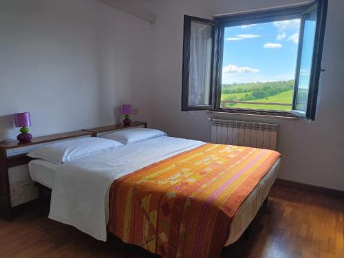 a bedroom with two beds and a large window at Agriturismo Podere Verdicchio in Scansano