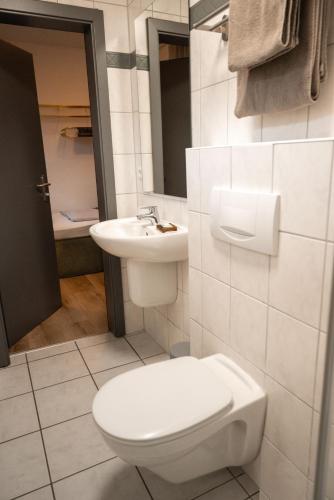 a white bathroom with a toilet and a sink at Landgasthaus & Hotel zur Krone in Dahn