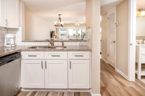 une cuisine blanche avec un évier et un miroir dans l'établissement Pier Point South Ocean View Townhouse Condo B-23, à Saint Augustine Beach