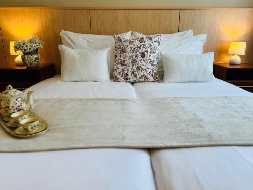 a large white bed with a tray of cookies on it at Plaza Hotel Gyula in Gyula