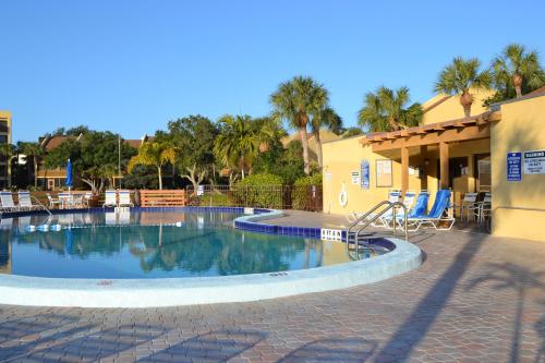 a swimming pool in a resort with chairs and palm trees at Midnight Cove II - Sunrise in Siesta Key