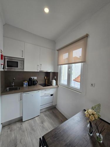 a kitchen with white cabinets and a wooden table at AquaChaves Apart Studios in Chaves