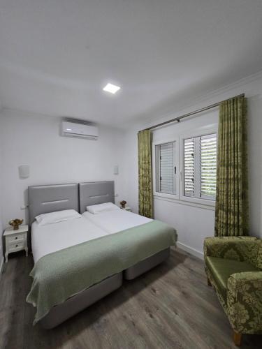 a bedroom with a bed and a chair and a window at AquaChaves Apart Studios in Chaves
