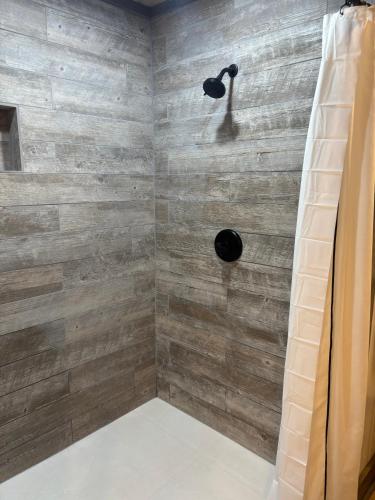 a bathroom with a shower with a wooden wall at Classy Bear Cabin in Gatlinburg