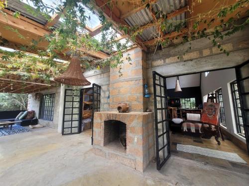 a living room with a brick fireplace and a room with a couch at DesertDewEstate in Nanyuki