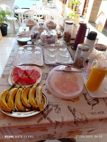 une table avec des assiettes de bananes et des verres de jus d'orange dans l'établissement Pousada ExtraLar, à Fortaleza