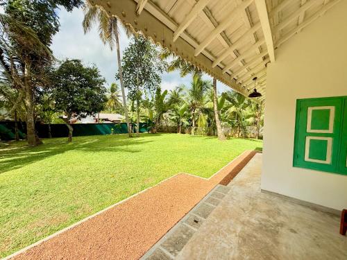 an outside view of a yard with a large lawn at Tropicana Hideaway Hikkaduwa in Hikkaduwa