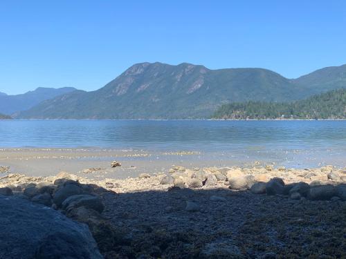 a beach with rocks and water with mountains in the background at Shoreside Private room in Sechelt