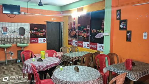 a dining room with two tables and red chairs at Dooars queen home stay in Chālsa Mahābāri