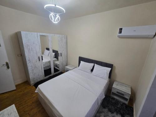 a bedroom with a white bed and a mirror at Alex Gate apartment - families only in Alexandria