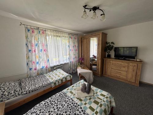 a bedroom with two beds and a flat screen tv at U Małgorzaty in Wojtkowa