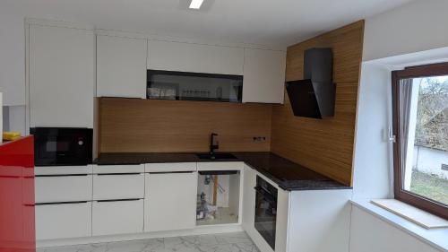 a kitchen with white cabinets and a sink and a window at Pferdeparadies Stein 