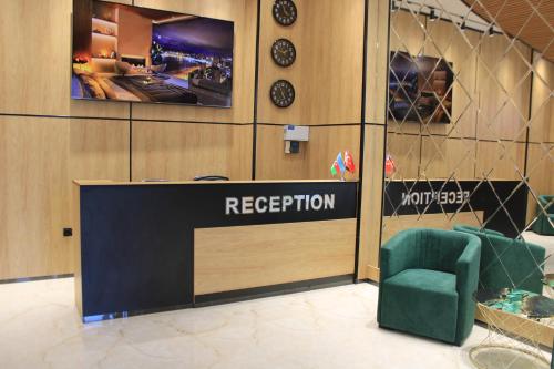 a reception desk with a green chair in a room at Xetai Royal Hotel in Baku