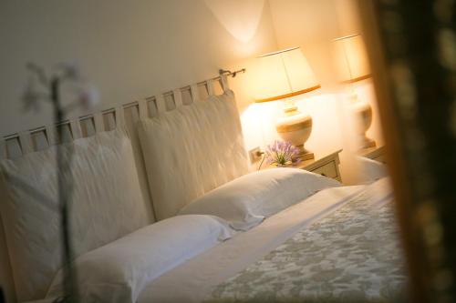 a bedroom with a bed with white sheets and a lamp at B&B Casa Dei Grilli in Longiano