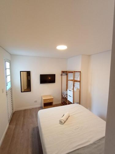 a bedroom with a white bed and a television at WeStay Nova Cidade in São Paulo