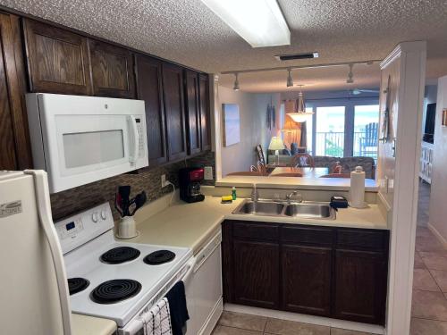a kitchen with a stove and a sink and a microwave at Relaxing Poolside Ocean View Townhouse Condo C-32 in Saint Augustine Beach