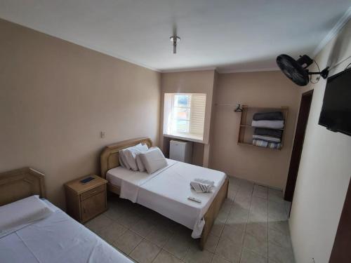 a small room with two beds and a television at Niv's Hotel in Monte Sião